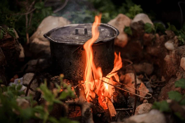 A cooking pot warming over an open campfire