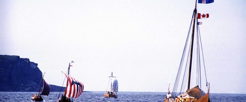 Reenactment of the Viking landing at L'Anse aux Meadows, Newfoundland, Canada, 2000. The foremost longship is flying, from top to bottom, the flag of Iceland, the flag of Canada, and the flag of Newfoundland and Labrador.