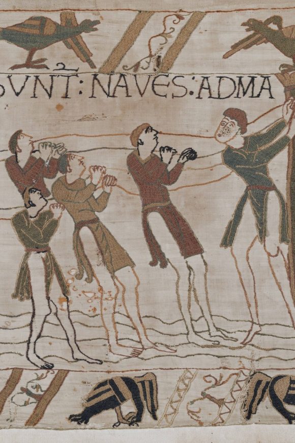 The Bayeux Tapestry: men pull together on ropes, hauling the new ships down to the sea