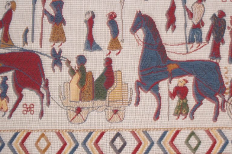 A modern woven reconstruction of the Oseberg tapestry: a horse-drawn wagon carrying cloaked figures in a procession, with riders and figures on foot