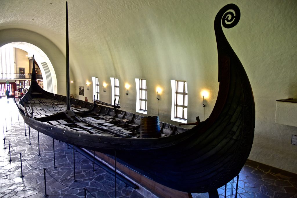 The whole Oseberg Viking ship, its carved spiral prow curling high, on display in the Viking Ship Museum in Oslo